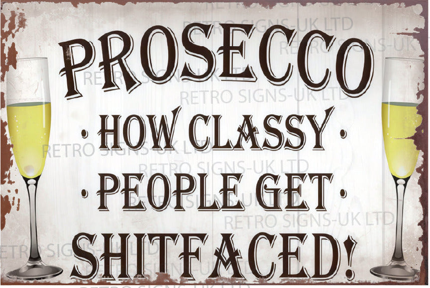 A rectangular vintage-style metal sign with the phrase “PROSECCO • HOW CLASSY • PEOPLE GET • SHITFACED!” in large dark lettering on a distressed off-white background. Two champagne glasses filled with pale yellow drink appear at the left and right edges.